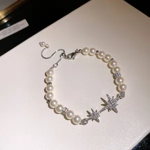 Macro view of 18k gold plated pearl bracelet with sparkling zirconia star charms.