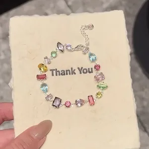 Gros plan d'un bracelet en zircone coloré sur une carte de remerciement crème