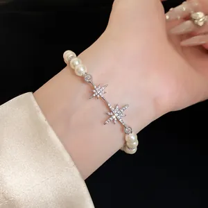Elegant pearl bracelet with sparkling star charms and silver-tone finish on wrist.