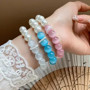Detailed view of sweet pearl and cat's eye beaded bracelets on a lace-cuffed wrist