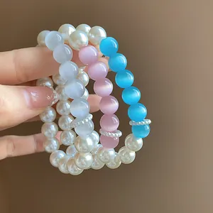 Close-up detail of elegant pearl and colorful cat-eye stone beaded bracelets for women