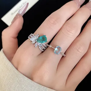 Gros plan de bagues élégantes en zircon avec des pierres vert poire et bleu ovale.