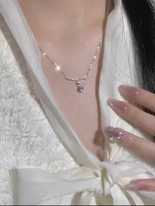Close-up detail of the sparkling zircon flower pendant necklace on a minimalist chain.