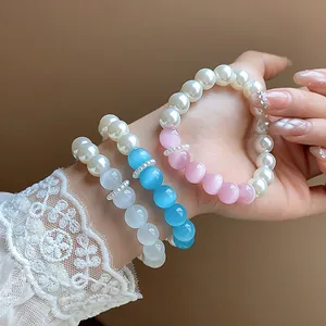 Detail showing elegant pearl and faceted cat-eye bead bracelets on a lace-sleeved wrist