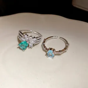 Gros plan de bagues argentées élégantes avec des zircons brillants verts et bleus.