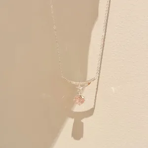 Close-up detail of silver necklace with pink zircon and star pendant on warm wall