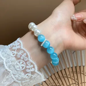 Detailed view of an elegant pearl and light blue bead bracelet worn on a woman's wrist