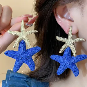 Detailed view showing blue woven raffia and gold textured starfish earrings on ear.