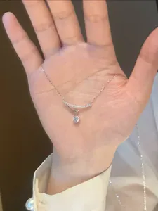 Detailed view of a silver necklace with a curved bar and sparkling zircon pendant