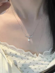 Close-up detail of minimalist silver necklace featuring a sparkling zircon pendant on model