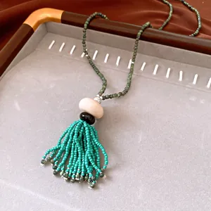 Close-up of vintage ethnic style necklace with green glass beads and turquoise tassel