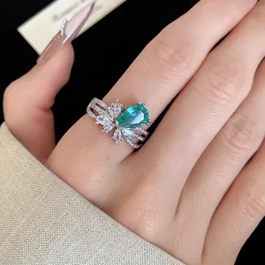 Gros plan d'une bague ouverte élégante à trois couches avec un zircon vert en poire