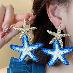 Detailed macro view of oversized raffia starfish earrings with gold metallic accents