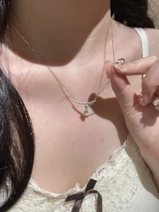 Close-up view of an elegant silver zircon curved bar pendant necklace worn by a model