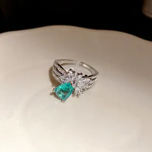 Détail macro d'une bague ouverte en argent avec zircon vert poire et accents de pétales