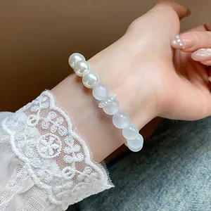 Close-up of elegant pearl and translucent bead bracelet worn on wrist with lace sleeve