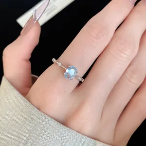 Vue rapprochée élégante d'une bague délicate en argent avec zircon bleu au doigt