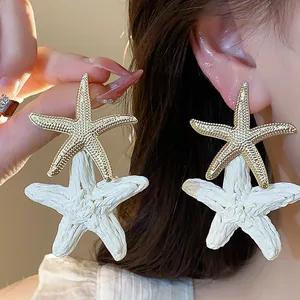 Detail shot showing the intricate texture of raffia and golden starfish holiday earrings.