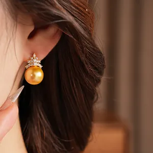 Gros plan d'une boucle d'oreille en perle dorée et zircons portées par un mannequin