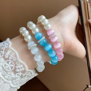 Close-up of three sweet pearl bracelets with white, blue, and pink cat-eye beads on wrist