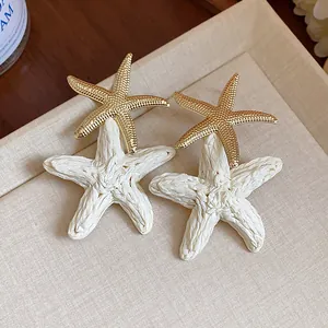 Detail showing the intricate raffia texture and golden finish on starfish earrings.