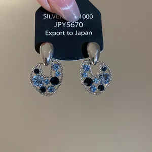 Primo piano di orecchini vintage in argento con strass blu su cartoncino