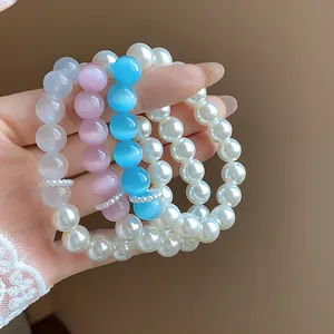 Close-up of elegant pearl and colorful cat-eye bead bracelets in soft pink and blue hues