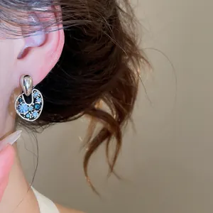 Primo piano di orecchini vintage rotondi traforati con strass blu brillanti sul lobo