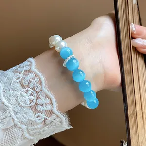 Detailed macro view of a sweet pearl and blue cat-eye bead bracelet on a wrist