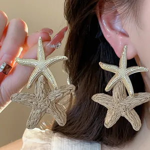 Detailed close-up showing textured gold and raffia starfish earrings on a model's ear