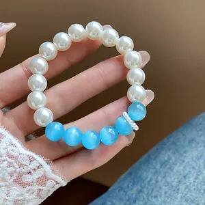 Detailed view of pearl and blue cat-eye bead bracelet on hand with lace sleeve