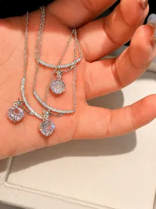 Detailed macro shot of three elegant shimmering zircon flower pendant necklaces held in a hand