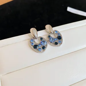 Dettaglio di orecchini vintage traforati con cristalli blu sfumati