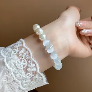 Close-up of elegant pearl and translucent stone bracelet worn on wrist with lace sleeve
