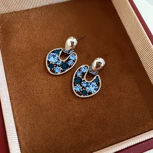 Dettaglio di eleganti orecchini vintage con cristalli blu in una scatola marrone