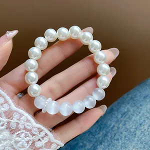 Close-up of elegant white pearl and translucent bead bracelet held by hand wearing lace sleeve