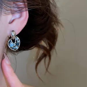 Primo piano di orecchini vintage traforati con strass blu e bianchi scintillanti.