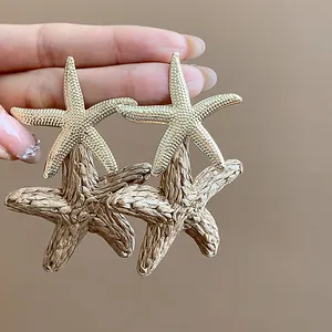 Detail view of gold-tone and raffia woven starfish earrings with textured finish