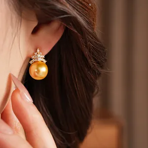 Vue détaillée d'une élégante boucle d'oreille en perle dorée avec un design de couronne en zircon