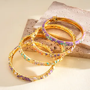 Nahaufnahme von Vintage-Armreifen mit bunten Emaille-Blumenmustern und glänzenden Strasssteinen