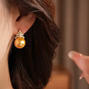 Gros plan d'une boucle d'oreille élégante en perle dorée et oxydes de zirconium