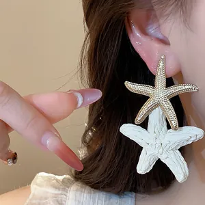 Detailed close-up showing stylish raffia and gold starfish earrings worn by a model