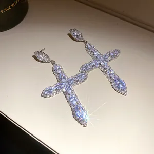 Detailed view of sparkling cubic zirconia cross drop earrings featuring silver needle posts