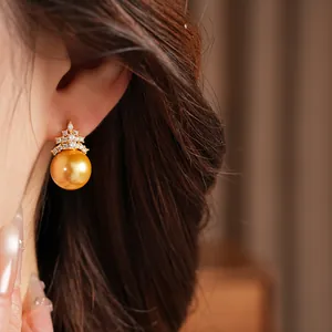 Détail en gros plan d'une boucle d'oreille en perle dorée avec zircons brillants