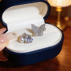 Dettaglio di orecchini a clip con farfalla in zircone e perla in astuccio
