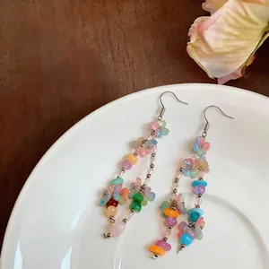 Detailed close-up of colorful resin flower beaded dangle earrings on a ceramic plate