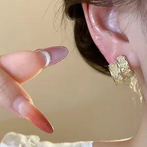 Close-up of elegant 14k gold-plated hoop earrings with detailed sparkling glass inlay