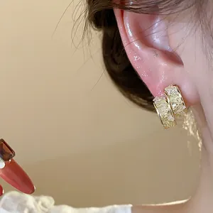 Close-up detail of 14k gold plated stud earrings with sparkling crushed glass inserts.