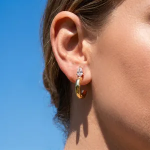 Close-up detail shot of a gold C-shaped hoop earring featuring a pear-cut cubic zirconia stud
