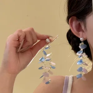Detailed view of long tassel pearl earrings with blue and pink petals for resort style